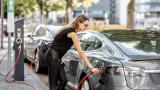 Woman charging electric car at the side of the road